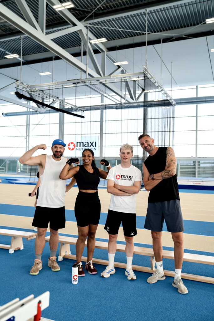 Stefan Joham, Chia Okpalaugo, Raphael Kokas und Clemens Doppler stehen auf einer Laufbahn, halten sich in den Armen und lächeln in die Kamera für ein Gruppenbild.