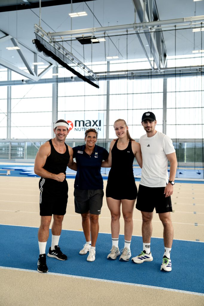 Alexander Schneller, Michi Dorfmeister, Teresa Mörtl und Ivo Buchta stehen auf einer Laufbahn, halten sich in den Armen und lächeln in die Kamera für ein Gruppenbild.