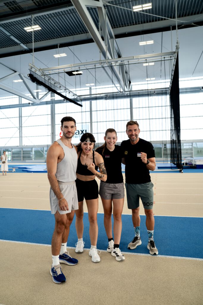 Philipp Gelter, Barbara Schwarz, Mariella Egarter und Andi Promegger stehen auf einer Laufbahn, halten sich in den Armen und lächeln in die Kamera für ein Gruppenbild.