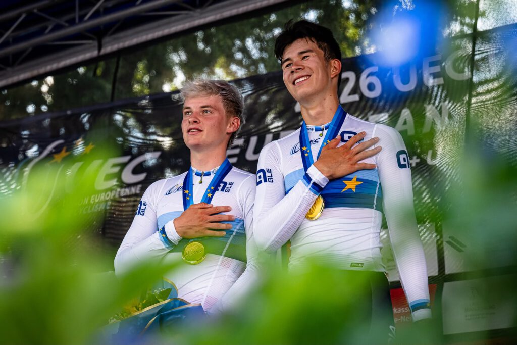 Raphael und Heimo bei der Siegerehrung. Der Blick geht in die Ferne und sie haben beide die Hand am Herz. Beide grinsen in die Ferne und tragen die Goldmedaille.